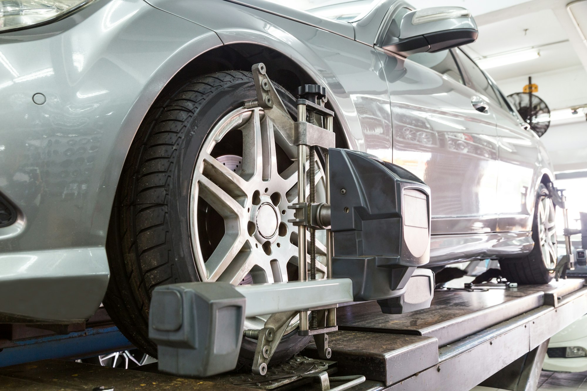Closeup of tire clamped with aligner undergoing auto wheel align
